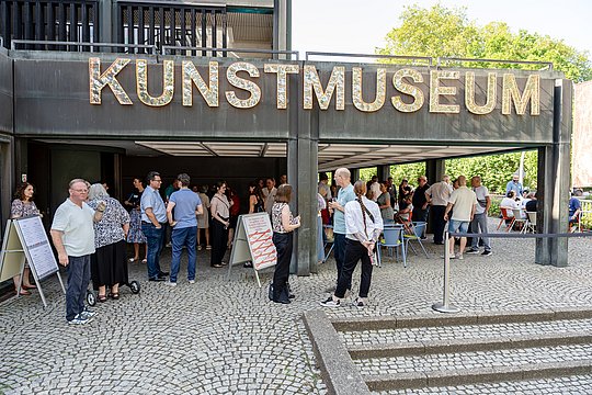 viele Menschen im Gespräch vor dem Museum